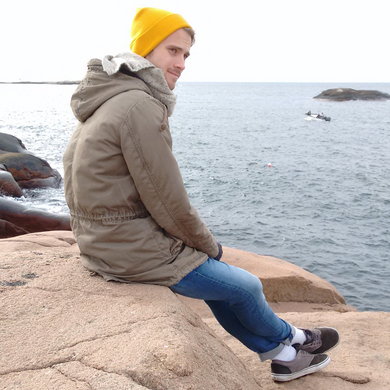 Tammo Schwier, sitzend auf einem Stein am Meer